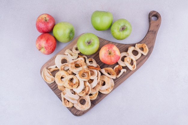 Bezpłatne zdjęcie suche plasterki jabłka na drewnianej desce z całymi jabłkami dookoła