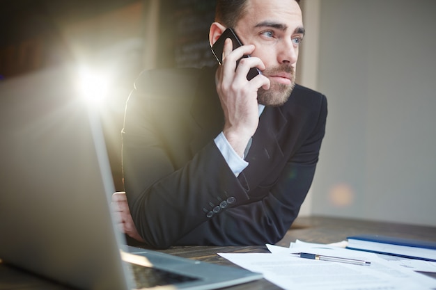 Bezpłatne zdjęcie sukcesy biznesmen dzwoniąc przez telefon podczas pracy