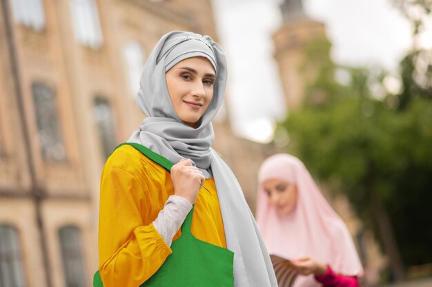 Sukienka i hidżab. piękna muzułmanka ubrana w żółtą sukienkę i hidżab stojący na zewnątrz