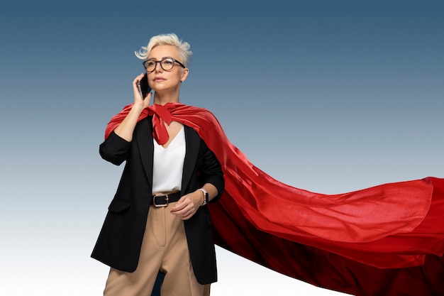 Bezpłatne zdjęcie superwoman z peleryną rozmawia na smartfonie
