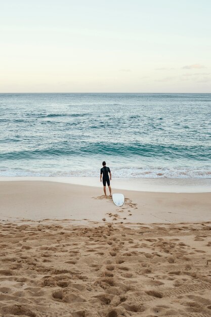 Surfer człowiek patrząc na morze pionowe długie ujęcie