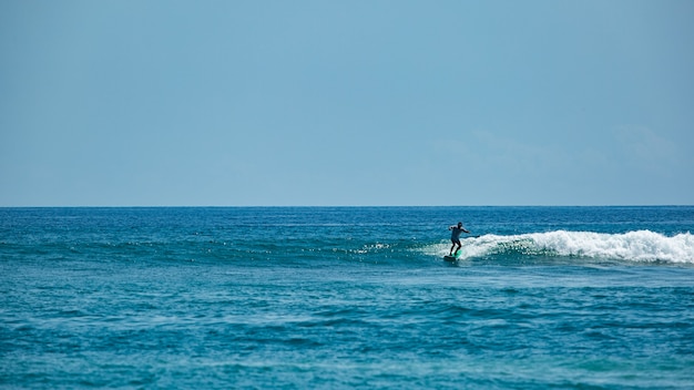 Surfer na błękitnej fali.