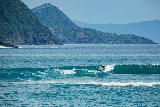 Surfer na błękitnej fali.