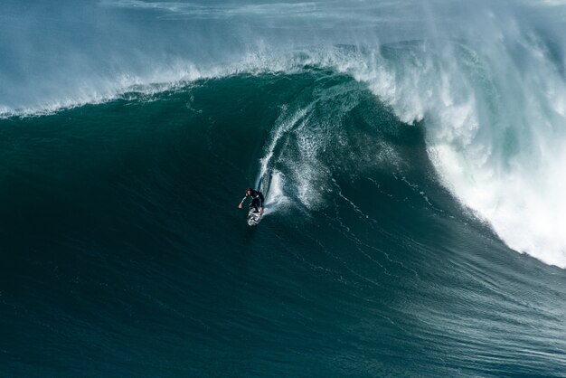 Surferzy jadący na falach Oceanu Atlantyckiego w kierunku brzegu w Nazare w Portugalii