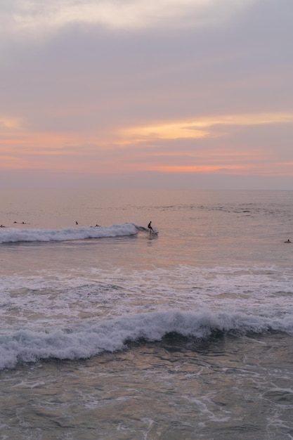 Surferzy łapią fale o zachodzie słońca w oceanie. Tło surfingu