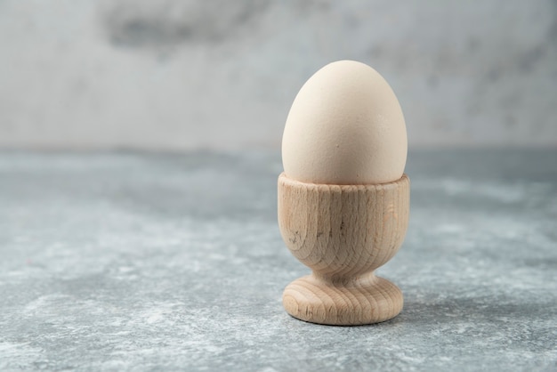 Surowe jajko w drewnianej misce na marmurowym stole.