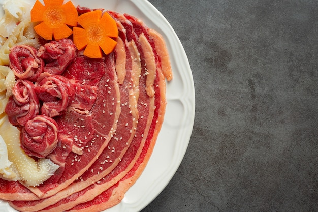 surowe mięso na białym talerzu do menu shabu z gorącym garnkiem