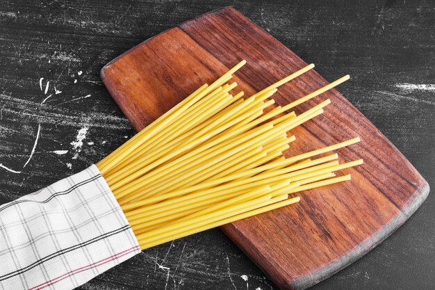 Surowe spaghetti na drewnianej desce.