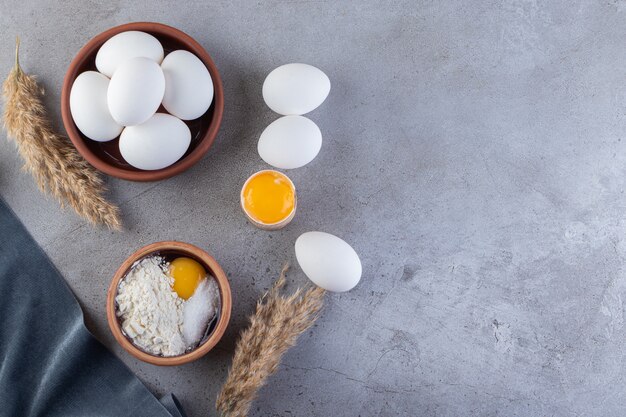 Surowe, świeże, białe jaja kurze umieszczone na kamiennej powierzchni.