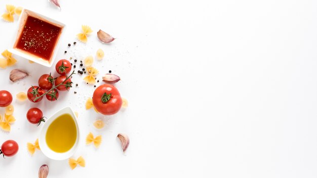 Surowy makaron farfalle z pomidorami; sos; ząbek czosnku na białym tle na białym tle