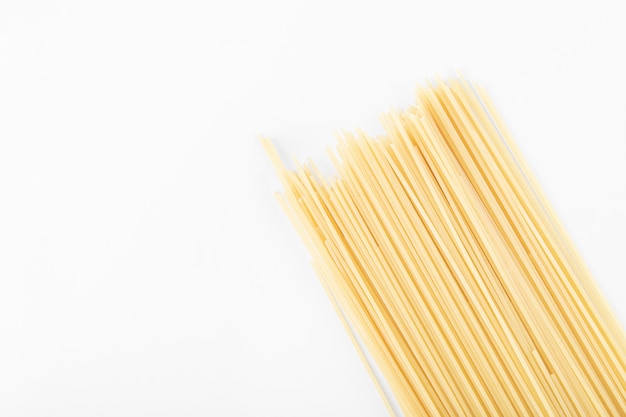 Surowy makaron spaghetti na białym tle.