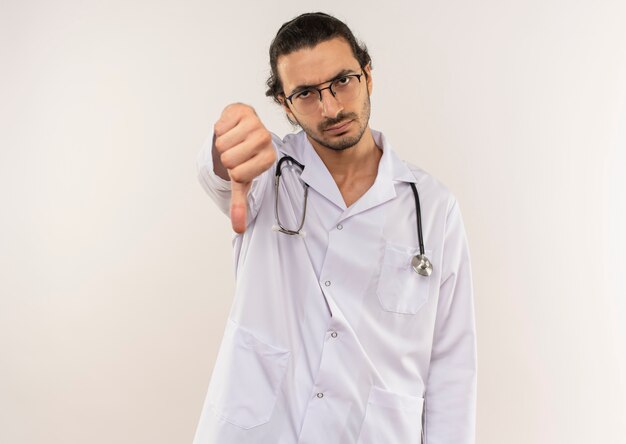 surowy młody lekarz mężczyzna z okularami optycznymi na sobie białą szatę ze stetoskopem kciuk w dół