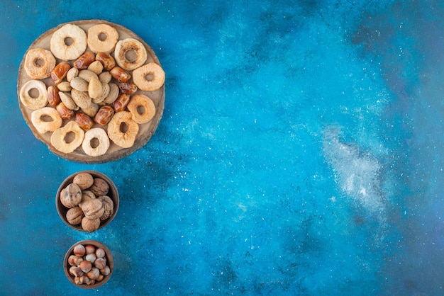 Bezpłatne zdjęcie suszone owoce i smaczne orzechy na desce na niebieskiej powierzchni