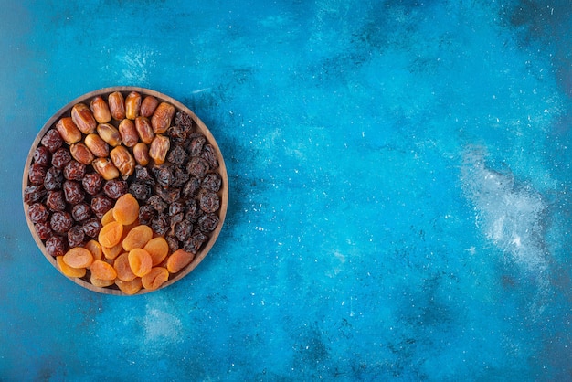 Bezpłatne zdjęcie suszone owoce na desce, na niebieskim stole.