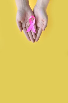 Świadomość raka piersi jestem i będę ręce kobiety trzymającej różową wstążkę na żółtym tle