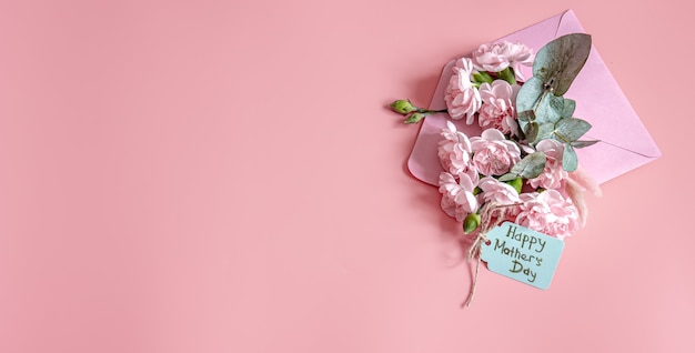 Świąteczna kompozycja z kopertą ze świeżymi kwiatami i napisem Happy Mother's Day flat lay.