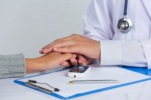 Bezpłatne zdjęcie Światowy dzień cukrzycy; lekarz, trzymając pacjenta za ręce