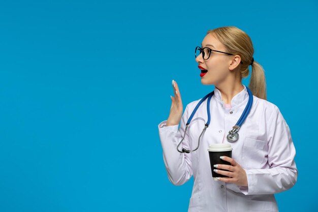 Światowy dzień lekarzy podekscytowany lekarz zakrywający usta kawą i stetoskopem w płaszczu medycznym