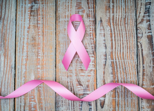 Bezpłatne zdjęcie Światowy dzień walki z rakiem: breast cancer awareness ribbon na drewnie backgr