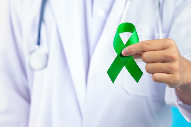Światowy Dzień Zdrowia Psychicznego. ręka lekarza trzymając zieloną wstążkę