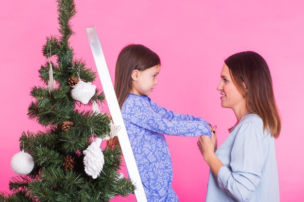 Święta rodzinne i święta koncepcja matka i córka dekorują choinkę na różowo
