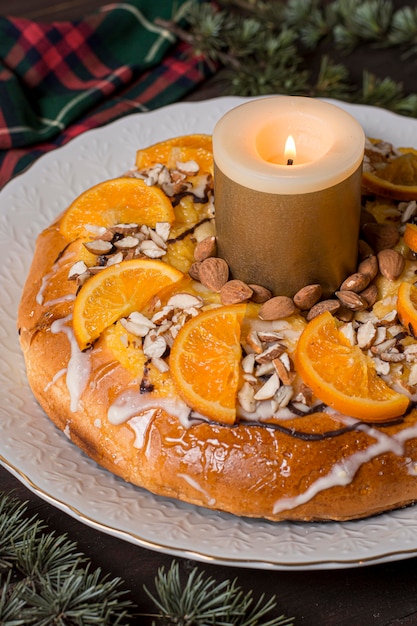 Bezpłatne zdjęcie Święto trzech króli jedzenie z plasterkami pomarańczy z zapaloną świecą z bliska