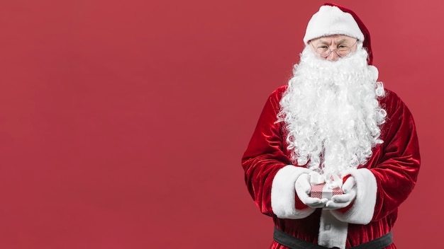 Święty Mikołaj w kapeluszu trzyma małego prezenta pudełko