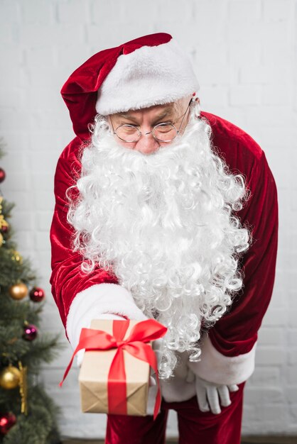 Święty Mikołaj w szkłach z prezenta pudełkiem w ręce