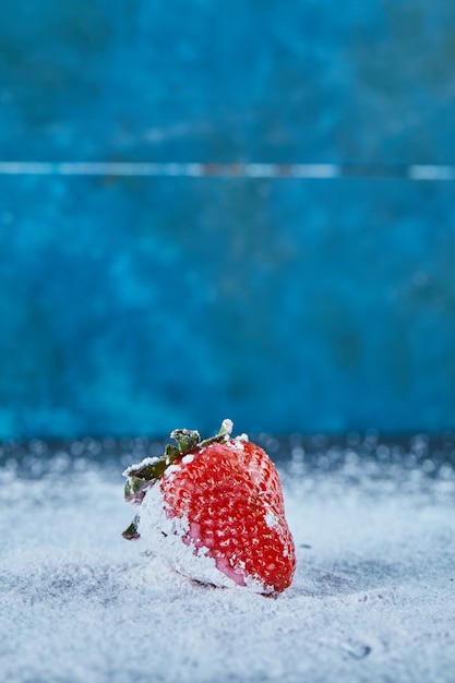 Świeża czerwona truskawka na niebieskiej powierzchni z proszkiem