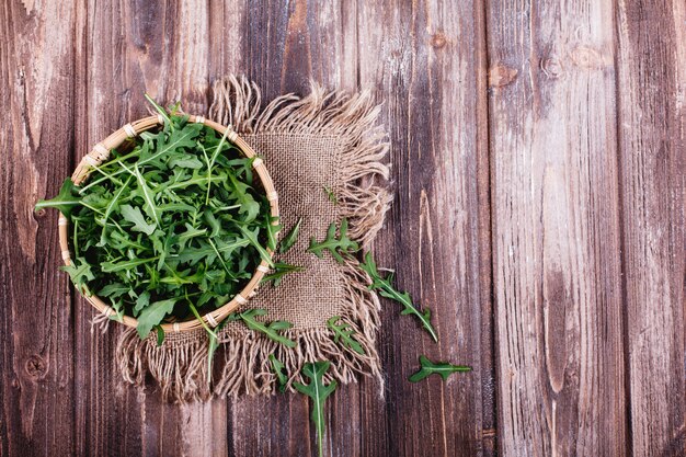 Świeża żywność, zdrowe życie. Zielony arugula słuzyć w pucharze na nieociosanym tle