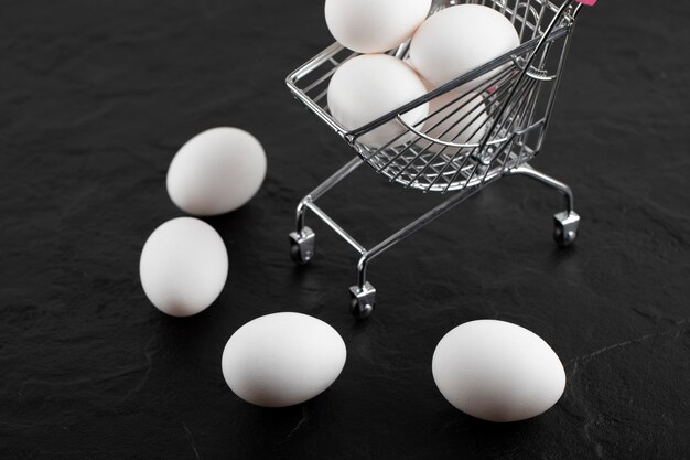 Świeże białe jajka w małym koszyku.