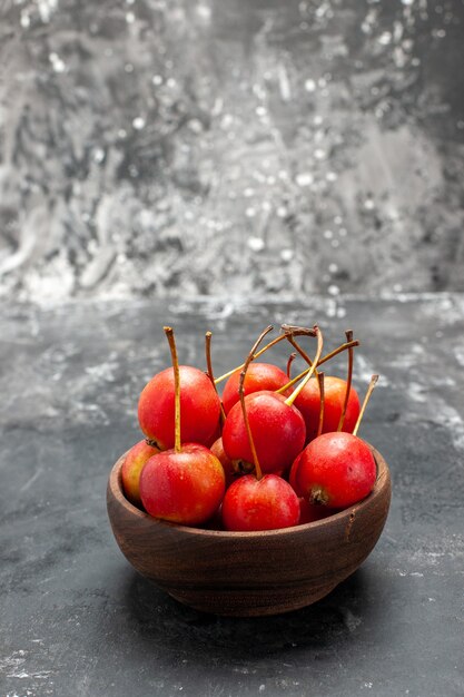 Świeże czerwone owoce wiśni w misce na szarym tle