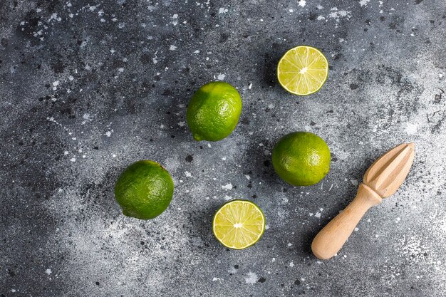 Świeże limonki z drewnianą wyciskarką do cytrusów, widok z góry