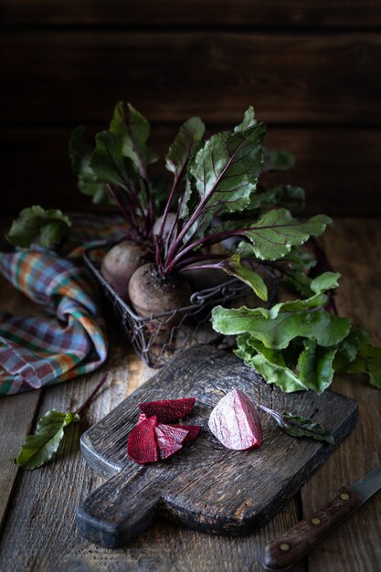 Świeże organiczne buraki czerwone z liśćmi w wiklinowym koszu na drewnianym stole. Naturalne organiczne warzywa. Jesienne zbiory. Rustykalny