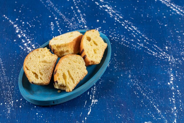 Świeże, smaczne ciasta w plasterkach umieszczone na niebieskim talerzu.
