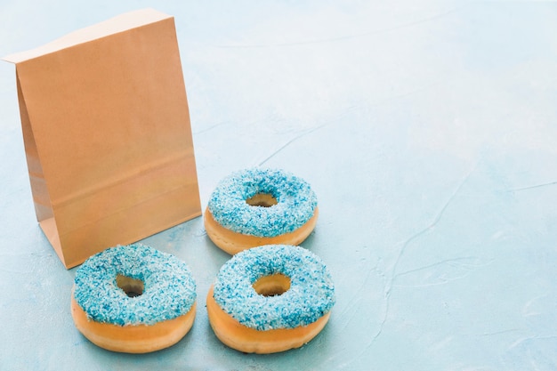 Bezpłatne zdjęcie Świezi donuts z pakunkiem na błękitnym tle