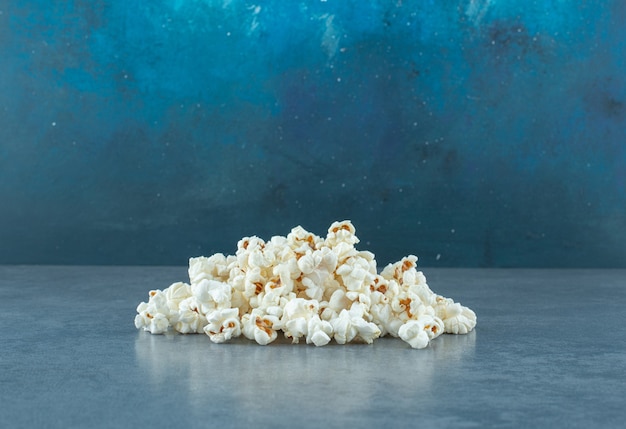 Świeżo gotowanie kupa chrupiącego popcornu na niebieskim tle. Zdjęcie wysokiej jakości