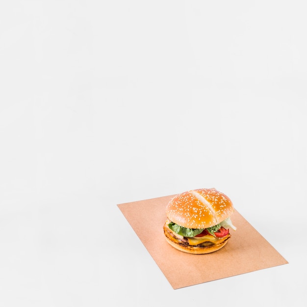 Świeży hamburger na brown papierze nad białym tłem
