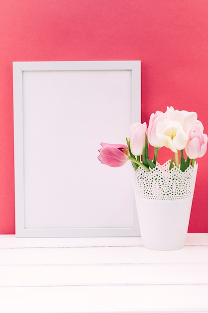 Świeżych kwiatów tulipanów w wazonie z pustą ramkę na zdjęcia