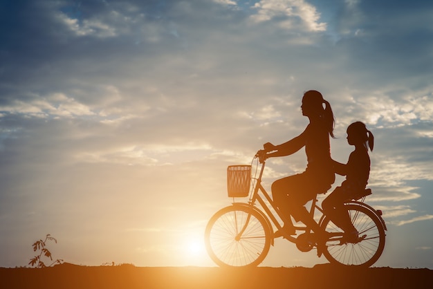 Sylwetka matka z jej córką i bicyklem