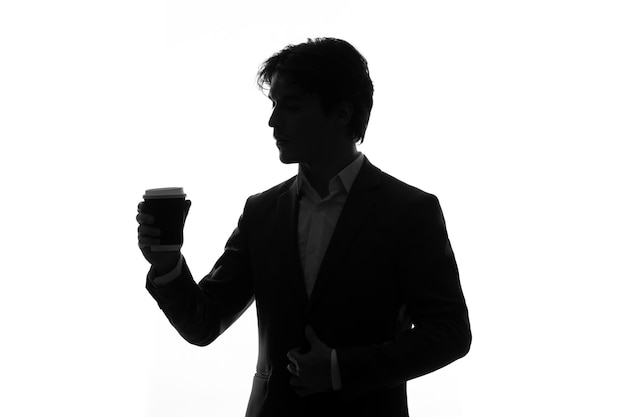 Sylwetka Mężczyzny W Garniturze Z Podświetlonym Białym Tle Kawy Cieniem Premium Zdjęcia