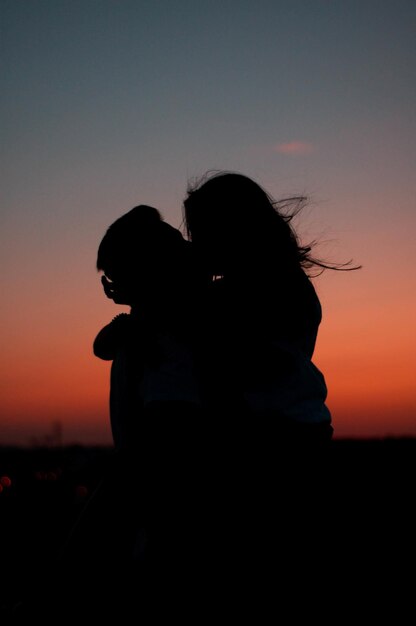 Sylwetka przytulającej się uroczej pary na tle barwnego, malowniczego zachodu słońca