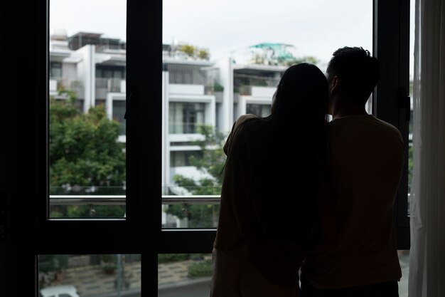 Sylwetka romantycznej pary przytulonej do domu i patrzącej przez okno