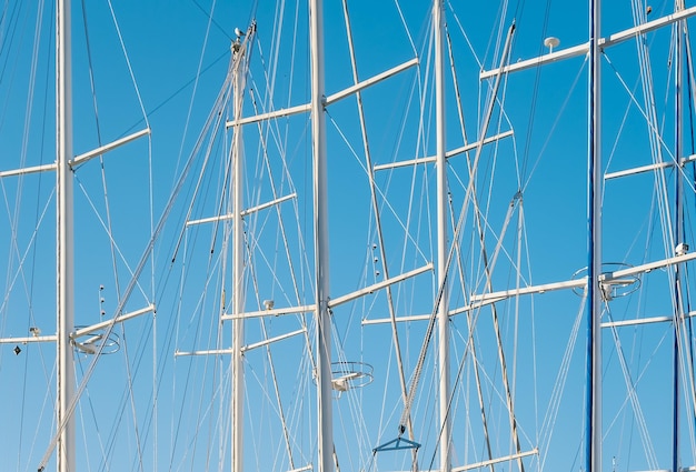 Bezpłatne zdjęcie sylwetki zapałek jachtów w marinie na tle czystego, błękitnego nieba pomysł na tło lub nowinki o żeglarstwie