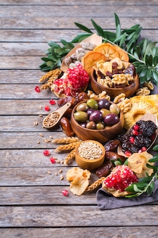 Symbole judaistycznego święta tu biszwat, rosz haszana nowy rok drzew. mieszanka suszonych owoców, daktyl, figa, winogrono, jęczmień, pszenica, oliwka, granat na drewnianym stole. skopiuj tło przestrzeni