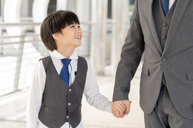 Syn trzyma rękę ojca w dzielnicy biznesowej miasta