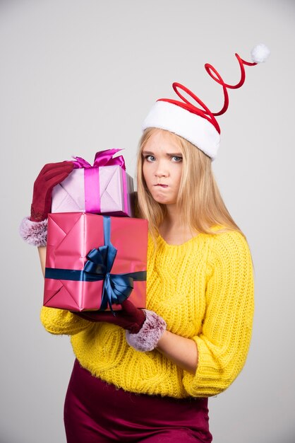 Szalony blond kobieta w Santa hat gospodarstwa prezenty świąteczne.