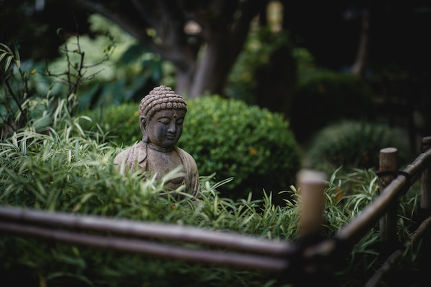 Bezpłatne zdjęcie szary budda w pobliżu posągu w pobliżu zielonych roślin