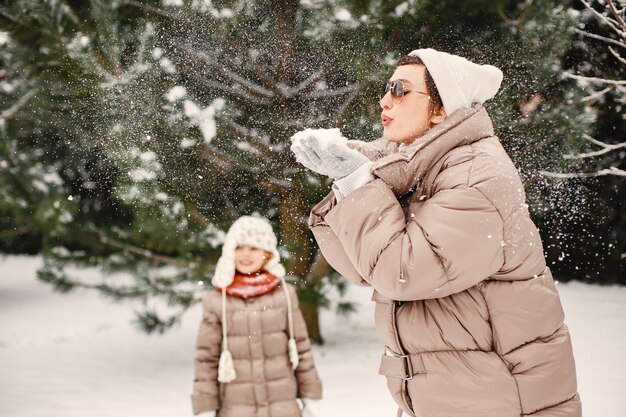 Szczegół portret kobiety w brązowej kurtce w śnieżnym parku z córką