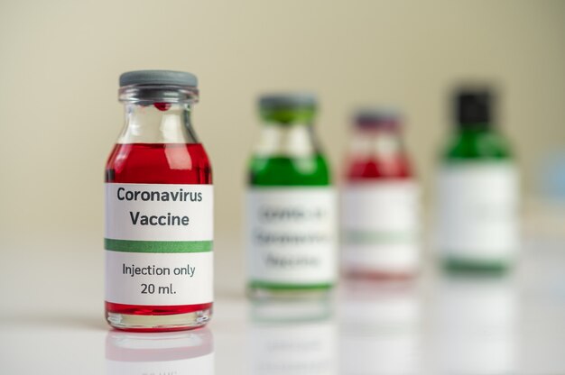 Szczepionka przeciwko Covid-19 jest w kolorze czerwonym i zielonym w butelkach umieszczonych na podłodze.